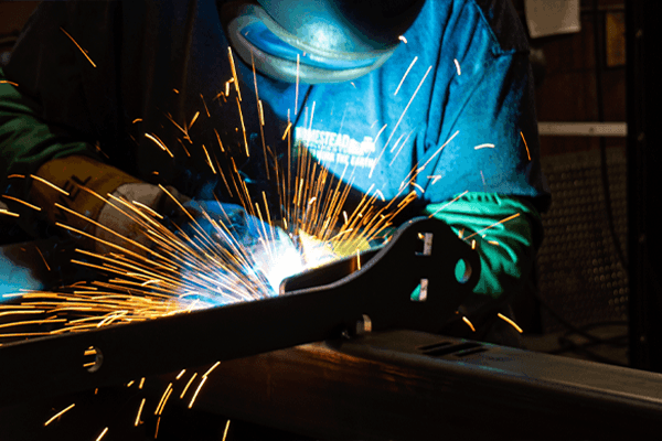 A welder welding a Homestead Implements attachment
